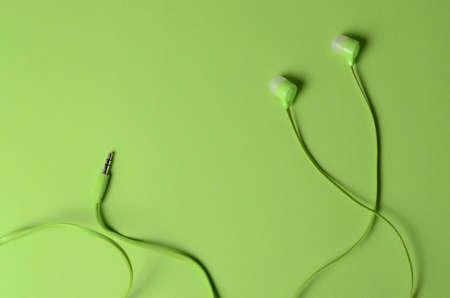Bright green headphones for the player on a similar green background. Monochrome concept for website design, postcards, advertising.の写真素材