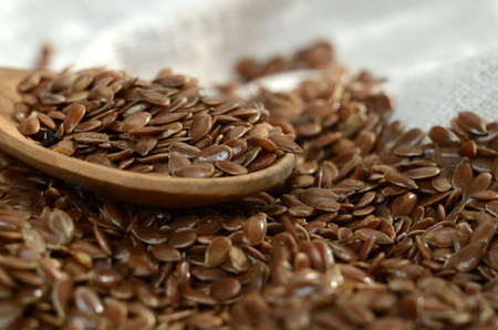 Close up flax seeds in the wooden spoon on linen textileの写真素材
