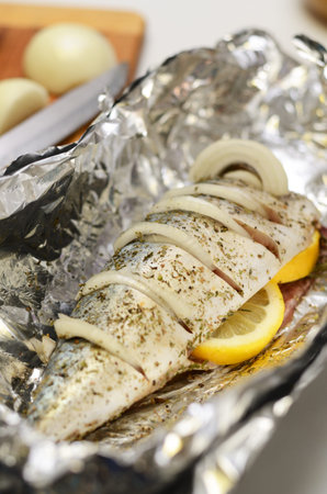 Fresh mackerel prepared for oven cooking, marinated with spices, salt and lemon. Raw fish in the foil.の写真素材