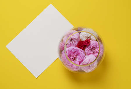 Roses on a glass vase, on a yellow background. flat lay still life photoの写真素材