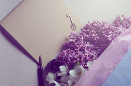 Romantic background with lilac flowers and notebook, sketchbook or diary. Spring season still lifeの写真素材