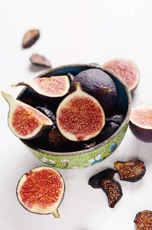 Fresh and dried deep blue figs in a green vintage boil covered by green enamel on a white wooden table.の写真素材