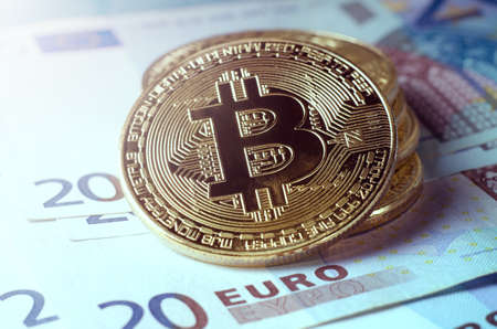 Physical Gold Bitcoin Coin against euro bills.の写真素材