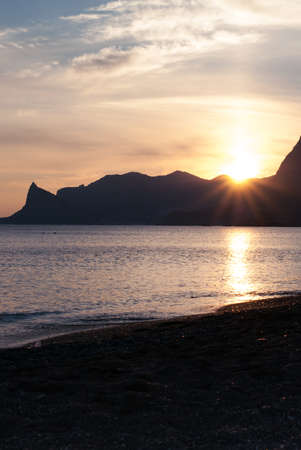 Beautiful bright sunset on the Black Sea in the Sudak. Seaside with outline of cape Kapchik. Crimea landscape.の写真素材