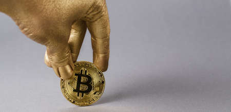 Golden hand holds physical coin of cryptocurrency bitcoin.の写真素材