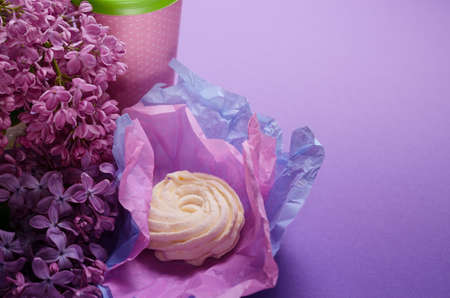 Food Photo of homemade zephyr, marshmallow in violet wrapping paper and coffee to go cup. Sweet dessert on a pink background.の写真素材