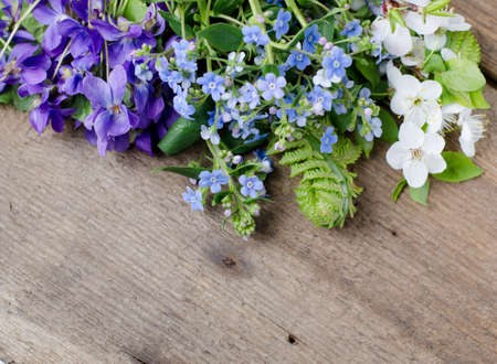 Spring bouquet with violets and forget-me-not flowers on a wooden background with space for text.の写真素材