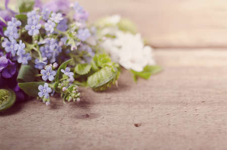 Spring bouquet with violets and forget-me-not flowers on a wooden background with space for text.の写真素材