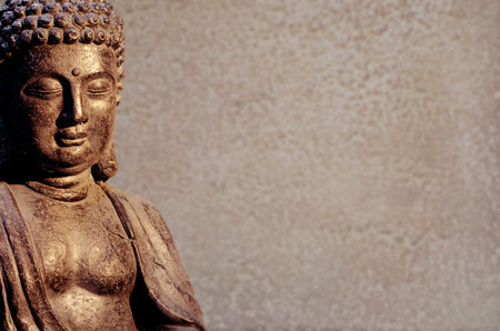 Buddha statue sitting in meditation pose against blurred background.の写真素材