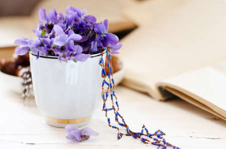 Still life with violet in white cup, old books. Romantic spring floral background.の写真素材
