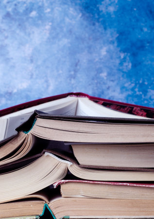 Stack of books piled against blue background. School concept.
