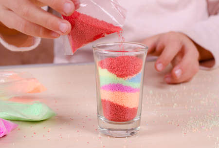 Making candles by yourself . Little girl making candle in the glass from soy wax parsley flakes.の写真素材