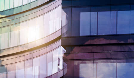 Geometric pattern from part of building facade with sun and clouds reflection. Modern architecture of commercial building walls made of glass. Abstract architecture background.の写真素材