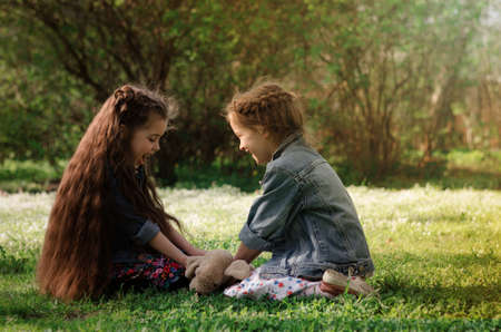 Two adorable little girls Playing in the a blossoming spring parkの写真素材