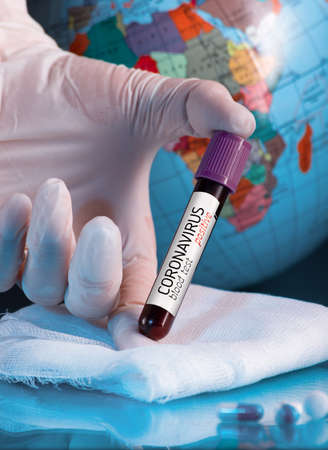 Human hand holding blood test semple in lab. Coronavirus 2019-nCoV concept still life with blood test, drugs and Earh Globe. COVID-19 background.の写真素材