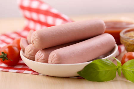 Boiled milk sausages with cherry tomato, ketchup and dijon mustard on a wooden table. Food promo poster template.の写真素材