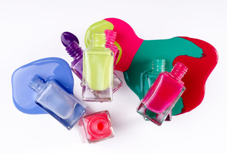 Nail polish tubes and bright colors of splash isolated on white background. Beauty industry concept backdrop.の写真素材