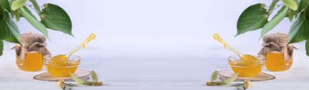 Banner template with Linden Honey in Jar and in bowl with a honey dipper on a white wooden table. Defocused branch of linden in the foreground.の写真素材