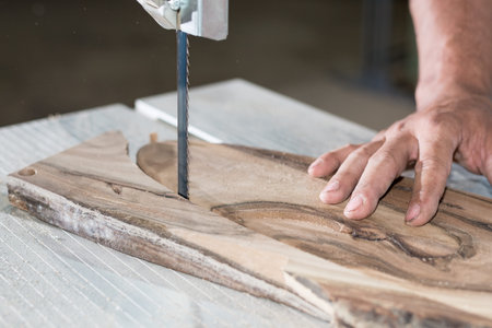 Close up Carpenter hands working on band saw with wooden shape to create interior products.