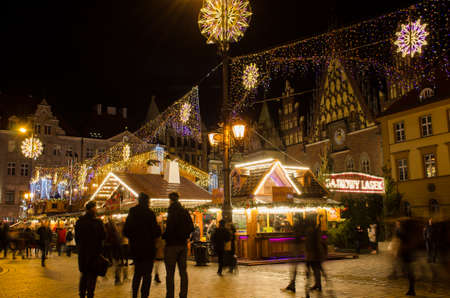 Wroclaw, Poland - 25.11.2019: Traditional Christmas Pyramid on the Festive Market of Rynek Square against Historic old town hall. Long lasting exposure.のeditorial素材