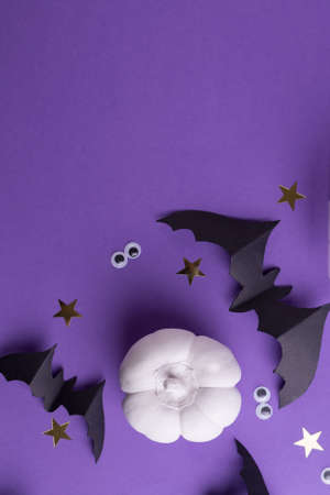Halloween frame template with black paper bats, white decorative pumpkins and plastic spooky eyes on a colored purple background.の写真素材