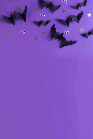 Halloween frame template with black paper bats and plastic spooky eyes on a colored purple background.の写真素材