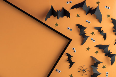 Halloween frame template with black paper bats and plastic spooky eyes on a colored yellow...