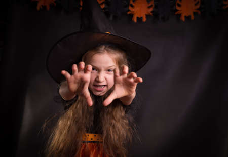 Happy laughing little girl wearing a witch carnival costume. Child girl Halloween kid against a white background.の写真素材