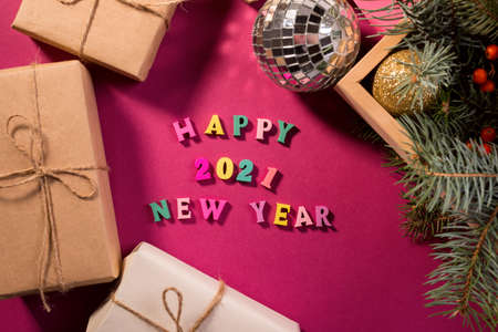 Happy New Year greeting words made of wooden letters, gift boxes on a purple background decorated with festive fir tree branches.の写真素材