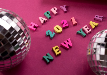 Happy New Year greeting words made of wooden letters, on a purple background decorated with stars...
