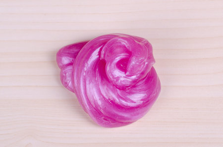 Cool handmade toy slime twisted in a poop form laying on a table. World wide trendy toy. Top-Down...