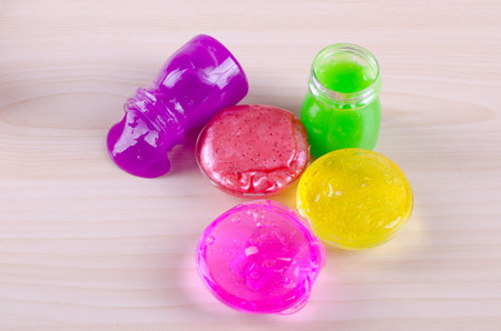 Bright multi colored slimes on a table. Kids most popular toy of nowadays. Slime in plastic containers.の写真素材
