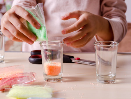 Making candles by yourself process. Little girl making candle in the glass from soy wax parsley flakes.の写真素材