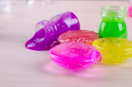 Bright multi colored slimes on a table. Kids most popular toy of nowadays. Slime in plastic containers.の写真素材