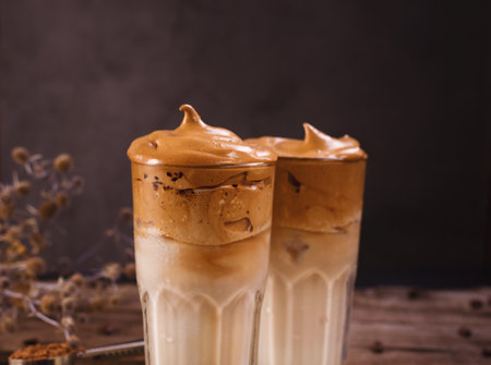 Dalgona Coffee. Whipped icing drink with instant coffee popular in Korea Creamy cocktail in tall Glasses. Dark moody food photographyの写真素材