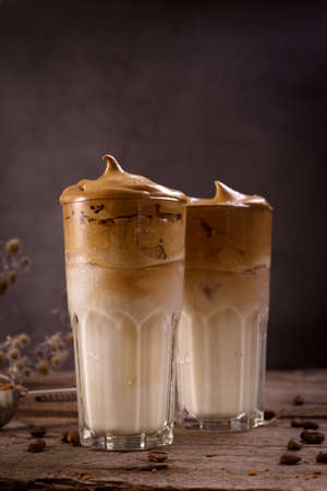 Dalgona Coffee. Whipped icing drink with instant coffee popular in Korea Creamy cocktail in tall Glasses. Dark moody food photographyの写真素材