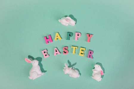 Holiday banner Happy Easter wooden words with cute decorative Easter bunnies on a turquoise background.の写真素材