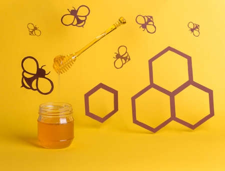 Honey jar among paper art, with paper cutter bees, and honeycombs, hexagons. Healthy sweets organic food concept.の写真素材