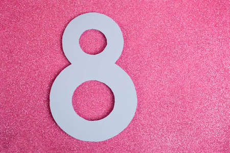 Number Eight cutted in paper against pink glitter background. Good for 8 march, international woman day vertical banner.の写真素材