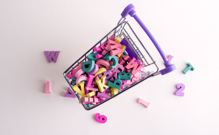 Plenty of wooden decorative letters in the small shopping trolley. Knowledge buying concept.
