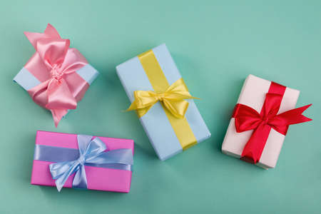 Different gift boxes with red, yellow. and blue bows on turquoise color background. Mothers day or minimalism concept to sale advertisingの写真素材