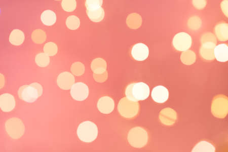 Beautiful calming coral color bokeh background. Happy New Year and Christmas backdrop with sparkling bokeh.の写真素材