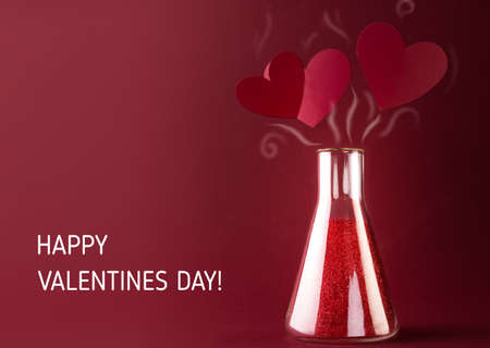 Love Chemistry, Happy Valentines Day card with Sparkling potion in Laboratory Glass Flask and Red hearts above it.の写真素材