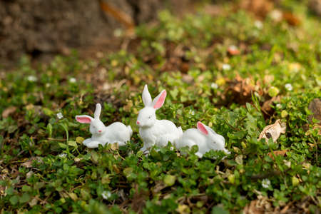 Cute Easter bunny figurine on a green moss of the forest. Spring seasonal Easter holiday backgroundの写真素材