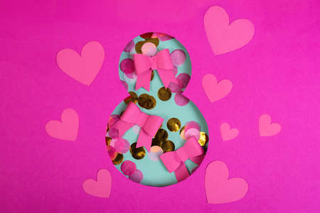 Paper art Eight number cut of bright pink paper against the turquoise background fulfilled by confetti paper bowsの写真素材