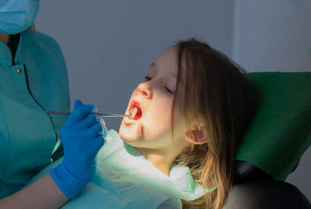 Process of Hygiene of Child Teeth. Little Girl in a chair of Dentist Hygienist during regular visit.の写真素材