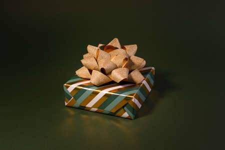 Boxing Day concept with gift boxes in gold and green colors decorated with sparkling bow against green color background.の写真素材