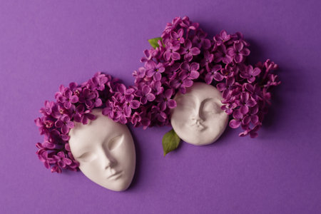 Plaster faces, figurine decorated with lilac flowers. Lilac as a hairstyle on the head figurine against blue background. Flat lay floral composition.の写真素材