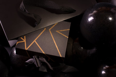Black Friday Shopping Concept with Black color gift box decorated with Gold Stripes laying on Black baloons.の写真素材