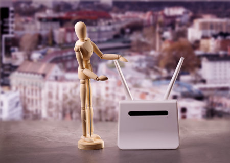 Wifi router and wooden mannequin. The wooden mannequin doll model presents a model of wifi router against blurred cityscape.の写真素材